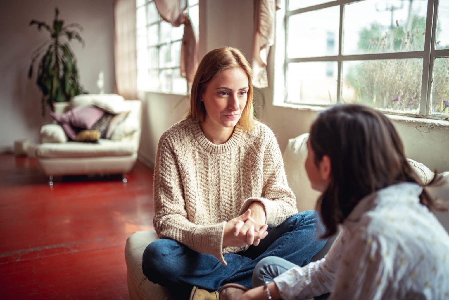 Middle aged woman sitting with a girl at home discussing aphasia.