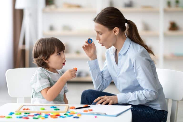 Auditory-Verbal-Therapy-session woman providing verbal therapy to a child - woman is holding up the letter o and the child is is mimicking the woman as they both practice the sound